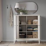 Organized storage cabinet IDANÄS with folded doors, white, holding clothes, boxes, and books. Stylish and functional.