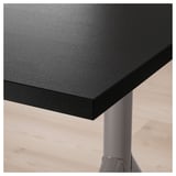 Black desk corner with thick, smooth tabletop supported by a sturdy metal leg.