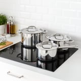 Modern kitchen with IKEA 365+ cookware set on black induction hob. Includes stainless steel pots, evenly heating with lids.
