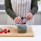Person seals food in clear IKEA 365+ jar, preserving freshness and visibility.