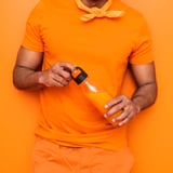 Man holding an orange IKEA 365+ plastic bottle with a black lid.