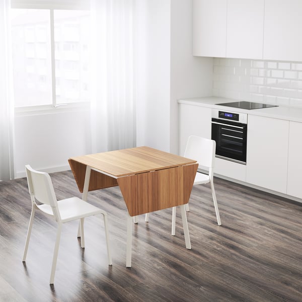 Modern white kitchen an IKEA PS 2012 bamboo drop-leaf table with two stacking white chairs, creating space-saving dining.