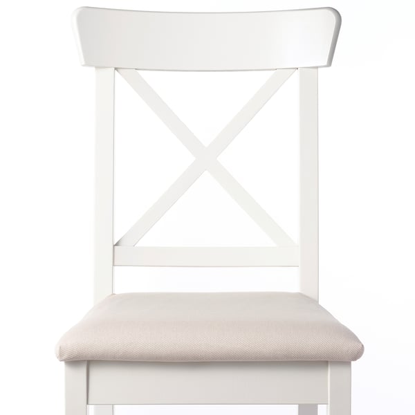 Modern dining chair with light beige upholstered seat, sturdy white wood frame, and x-back design for durability and style.