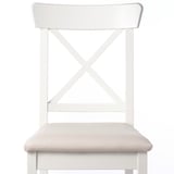 Modern dining chair with light beige upholstered seat, sturdy white wood frame, and x-back design for durability and style.