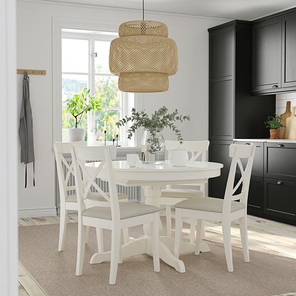 INGATORP white dining set with extendable table, 4 chairs, beige cushions, tiered pendant light, dark cabinets, rug, greenery.