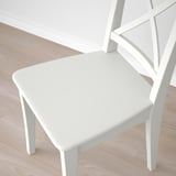 White chair with sleek, modern design. Made of sturdy wood and smooth acrylic paint. Comfortable, high back and minimalist style.