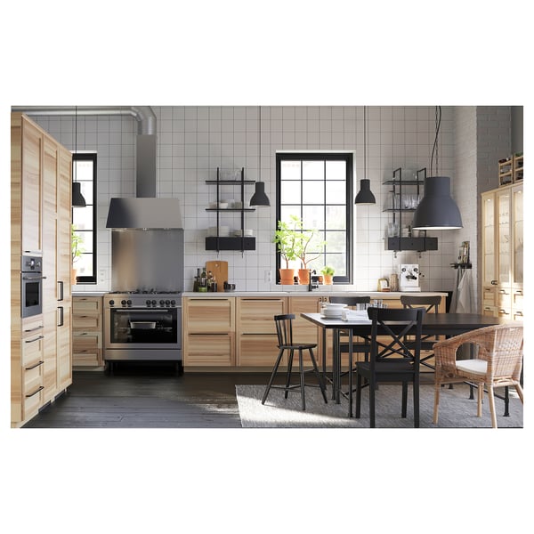 Modern kitchen with wooden cabinets, steel appliances, and wicker-seat table. White backsplash, large window.