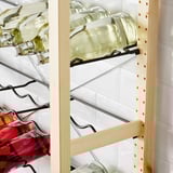Shelf unit holding green glass bottles, part of the IVAR storage system, ideal for various rooms.