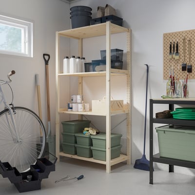 IVAR storage unit in natural wood, holding various items, against wall with window.