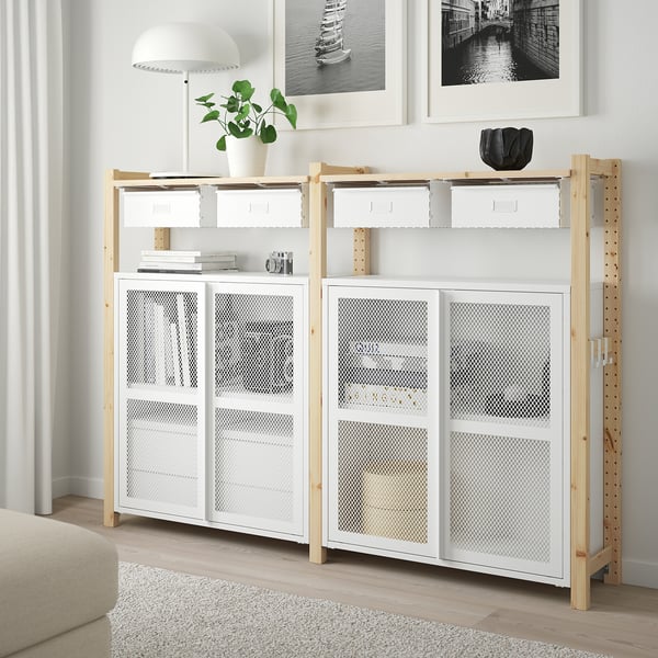 IVAR storage unit with boxes, lamp, and plant beside sofa.