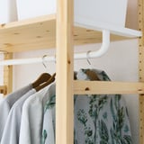 Wooden IVAR wardrobe with clothes rail hanging shirts; includes wire shelf and cover.