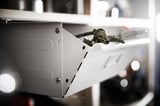 White IVAR drawer, slightly open front, steel frame, rope handle, mounted on wall.