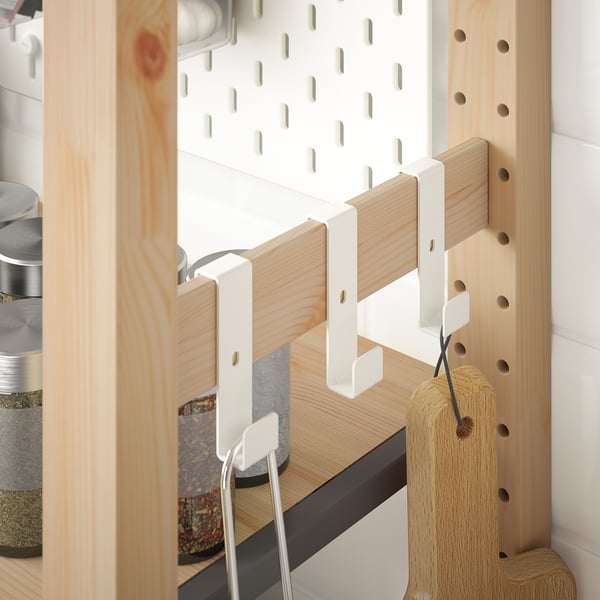 A wooden IVAR shelf with hooks holding kitchen items, maximizing storage space.