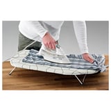 Person ironing blue striped shirt on foldable, steel-framed ironing board.