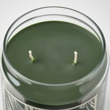 Glass candle jar with dark green wax and two unlit white wicks.