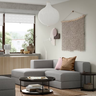 Modern living room with gray JÄTTEBO modular sofa, pillows, coffee table, large window, wall hanging, and pendant lamp.