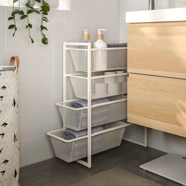 White JONAXEL storage rack with towels, bottles; between cabinet & wall, plant left