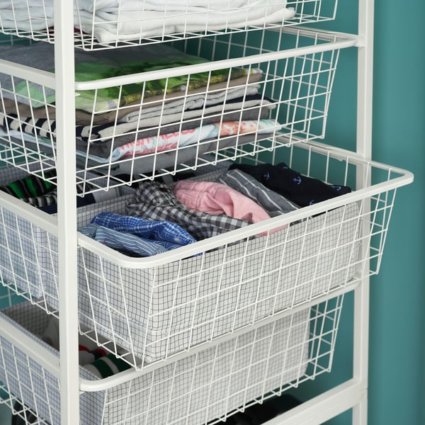 A white JONAXEL storage unit with multiple wire baskets holding folded clothes. Each basket is rectangular and stacked vertically.