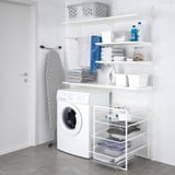 Laundry room with JONAXEL shelves holding towels, detergent, basket, washing machine, and ironing board.
