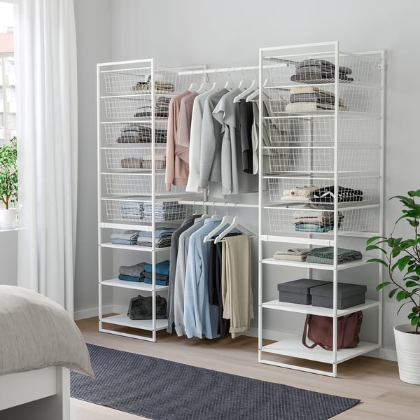 White JONAXEL storage system with metal frames, shelves, and hangers in bedroom, larger than the nearby rug and plants.
