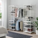 White JONAXEL storage system with metal frames, shelves, and hangers in bedroom, larger than the nearby rug and plants.
