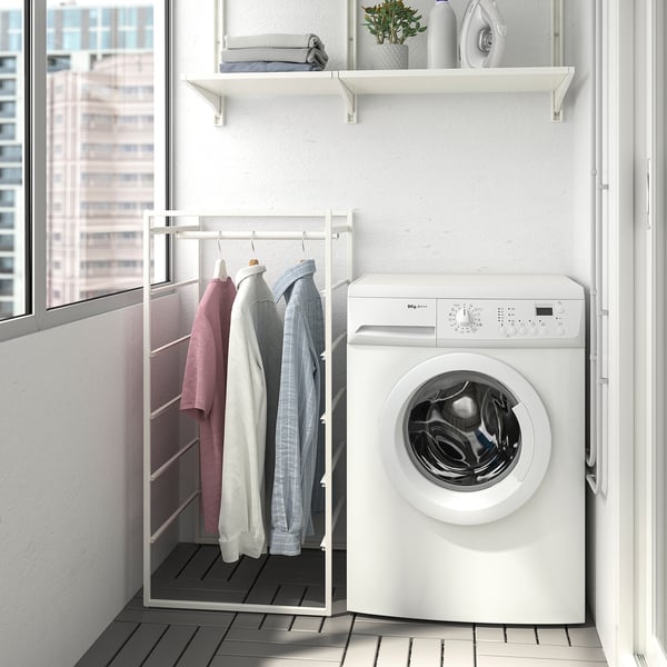 Compact laundry setup: JONAXEL rack with shirts, washing machine, and shelf with towels.
