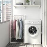 Compact laundry setup: JONAXEL rack with shirts, washing machine, and shelf with towels.