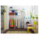Laundry room with JONAXEL shelves, clothes, washing machine, yellow chair, colorful decor.