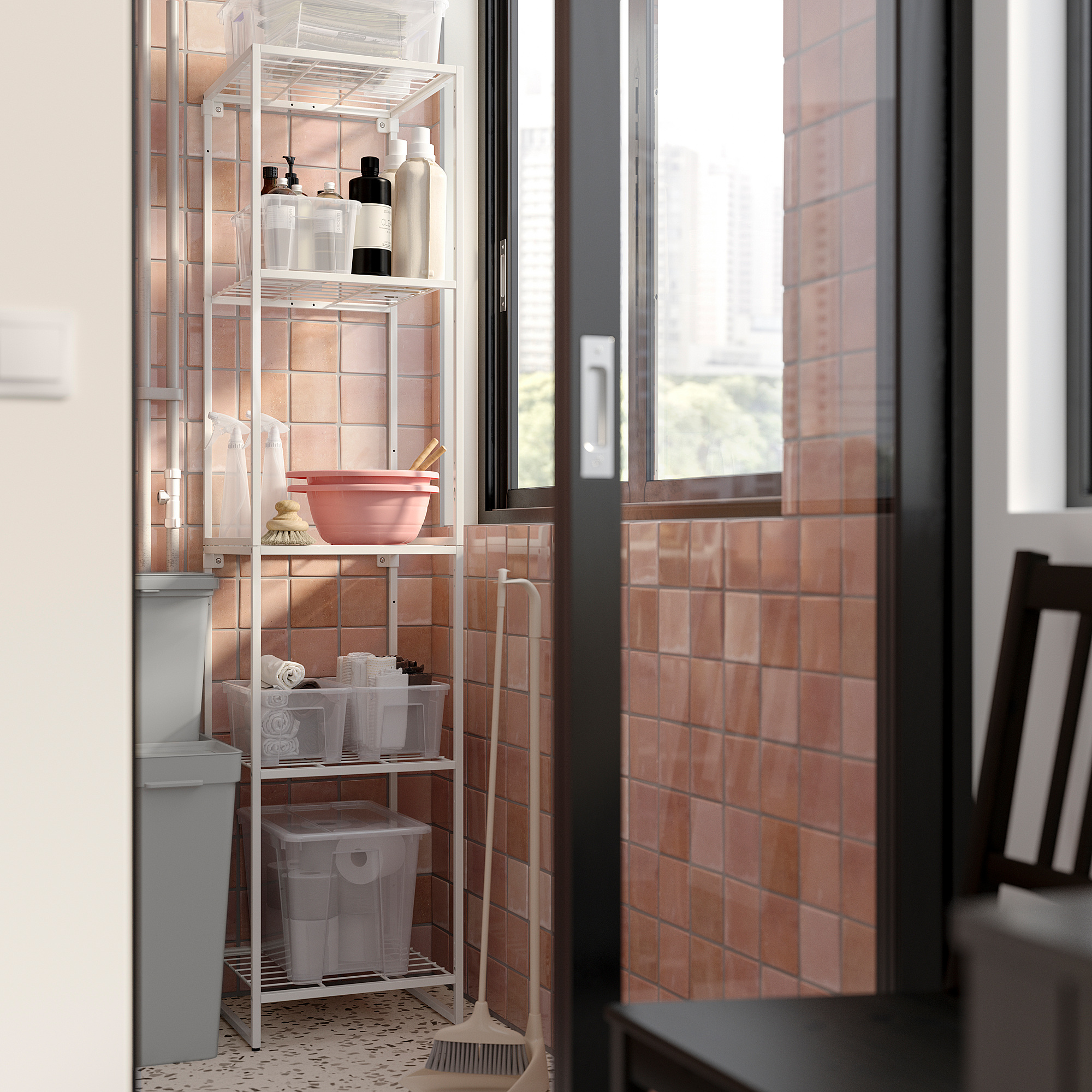 JOSTEIN white metal bathroom shelf, holding cleaning supplies and items, against pink tiled wall.