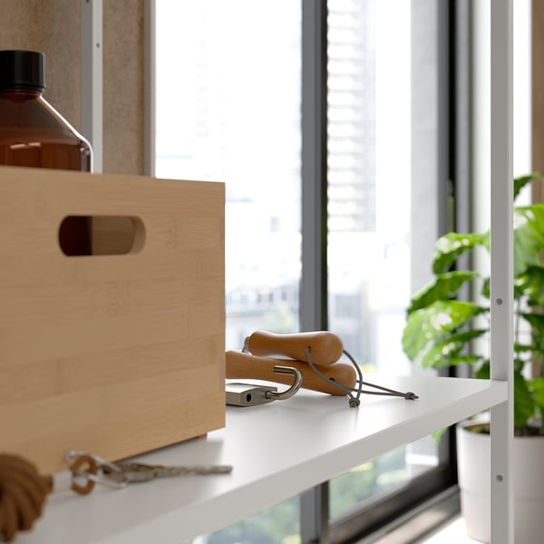 White shelf unit near window with wooden box, skis, keys, and plant.
