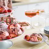 Pink cream cakes with strawberries and raspberries, cocktails, and dessert plates.