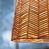 Close-up of a woven, illuminated lamp shade with a herringbone pattern, crafting warm, ambient light.