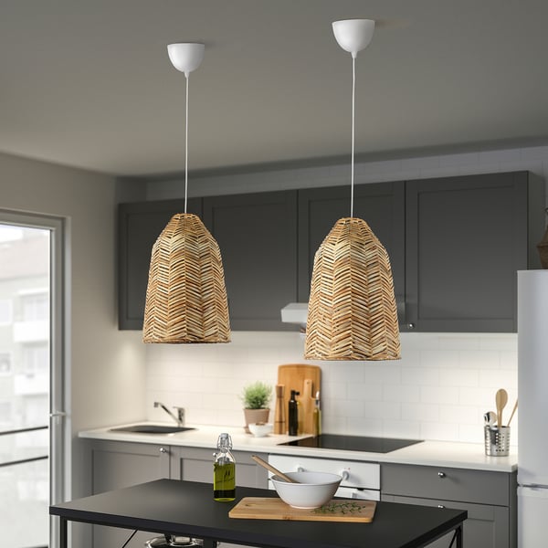 Two KAPPELAND rattan pendant lamps illuminate kitchen island, contrasting with gray cabinets and white backsplash. Cozy ambiance.
