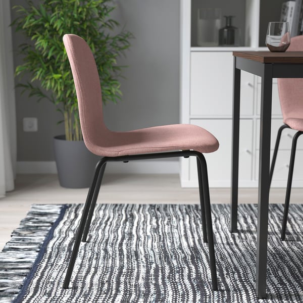 Pink cushion chairs on rug near table.