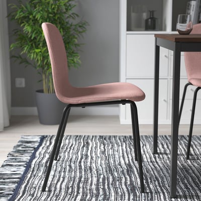 Pink cushion chairs on rug near table.