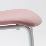 Close-up of a pink chair seat, showing its soft, smooth texture and sturdy light-colored metal frame.