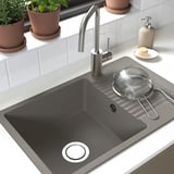 Black sink with stainless faucet and strainer; plants nearby.