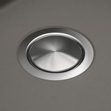 Stainless steel sink drain cover, smoothly integrated into a dark quartz countertop, showcasing durability and seamless design.