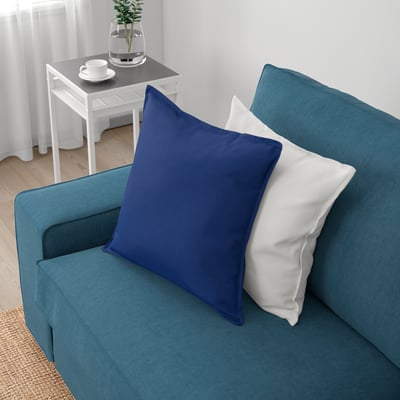 Blue KIVIK sofa with deep seat cushions, two throw pillows, and white side table with plants and cups.