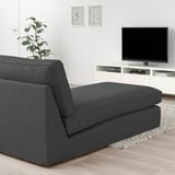 Modern living room with dark gray KIVIK sectional sofa, wooden floor, white tv stand, and wall art. Sofa appears large compared to other items.