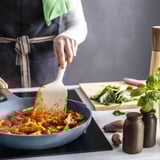 Cooking in blue pan with spatula.