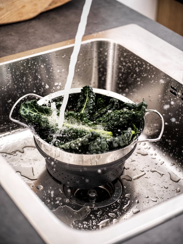 Stainless colander rinsing greens.