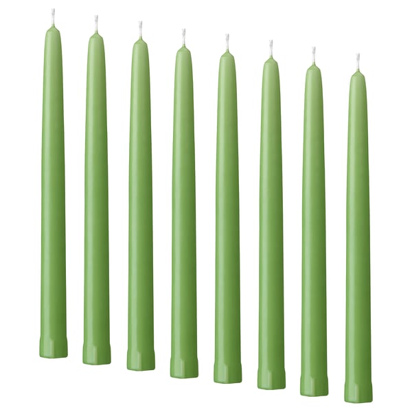 Eight green KLOKHET candles in a row, tall and straight, uniform color and shape, made of stearin.