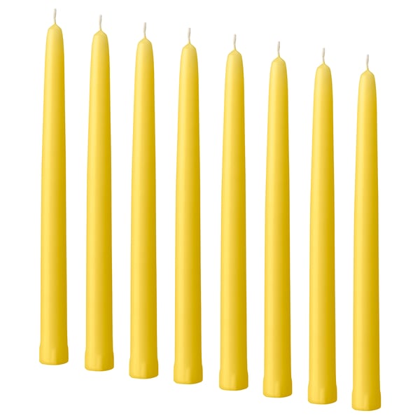 Eight yellow candles, thin and straight, lined up neatly. Made of stearin, they stand upright with cotton wicks.