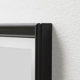Black picture frame corner, securely attached to a white textured wall.