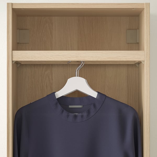 A wooden closet unit with a hanging rail displaying a navy blue garment on a white hanger.