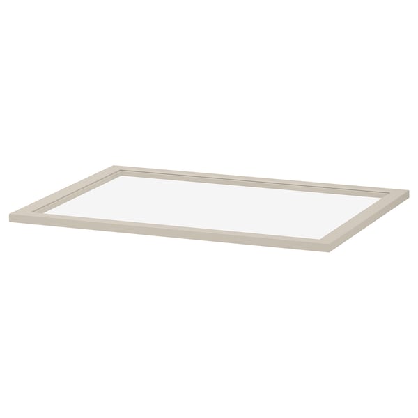 A KOMPLEMENT glass shelf in beige. It has a rectangular shape with a fibreboard frame and tempered glass centre, designed for wardrobe storage.