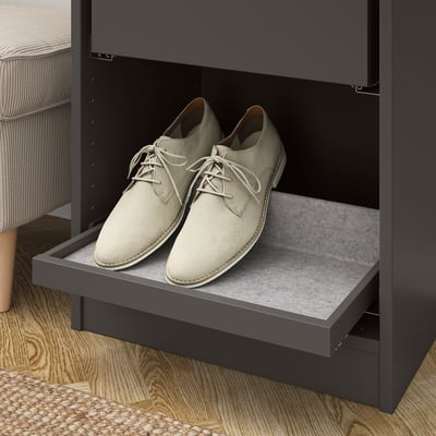 A gray wardrobe compartment with pull-out tray holding beige shoes, showcasing organized storage with rails and non-slip felt.