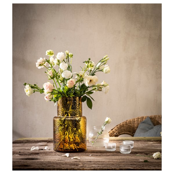 Image a KONSTFULL amber glass vase with white flowers on a wooden table.