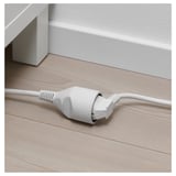 White extension cord on wooden floor. Provides power where needed.